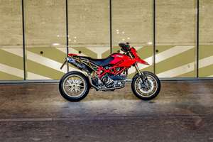 Ducati Hypermotard 1100 — Fiancata destra completa davanti a una vetrata con grafica a chevron.