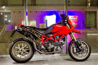 Ducati Hypermotard 1100 — Fiancata destra in un atrio illuminato di viola, scalinata a sinistra.