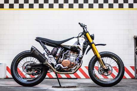 Una moto finita nell'officina di Meccanica Serrao D'Aquino a Milano, davanti alla parete piastrellata con la fascia a scacchi.