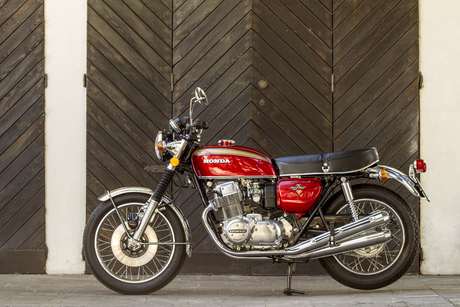 Honda 750 Four — Fiancata sinistra completa davanti a un portone di legno a spina di pesce.