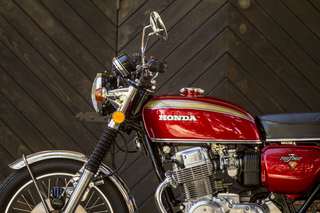 Honda 750 Four — Tre quarti anteriore sinistro: faro, manubrio, serbatoio rosso con filetto oro.