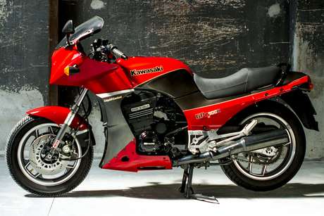 Kawasaki GPZ 900 — Fiancata sinistra completa sul cavalletto, muro di cemento scuro.