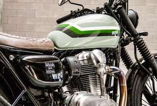 Kawasaki W800 — Serbatoio, testata e sella trapuntata da destra, muro di mattoni chiari.