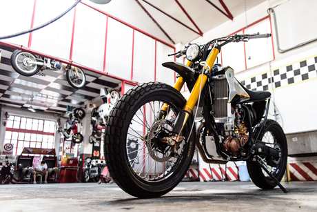 L'interno dell'officina: moto appese al muro, capriate rosse, il banco di lavoro.