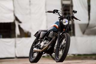 Yamaha SR 500 — Tre quarti anteriore destro dal basso, faro acceso, fondale di teloni bianchi.